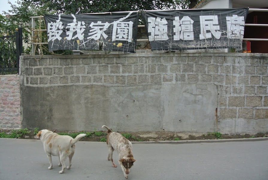 Banner in Ka Ho Village: Destroy my home. Grab my fortune.